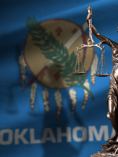 The justice statue in front of the Oklahoma state flag.