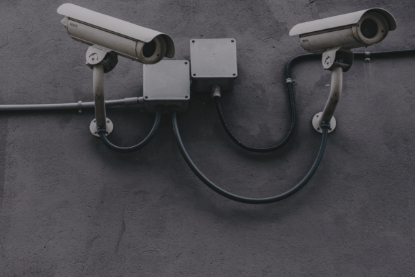Image of white security cameras against a grey wall.