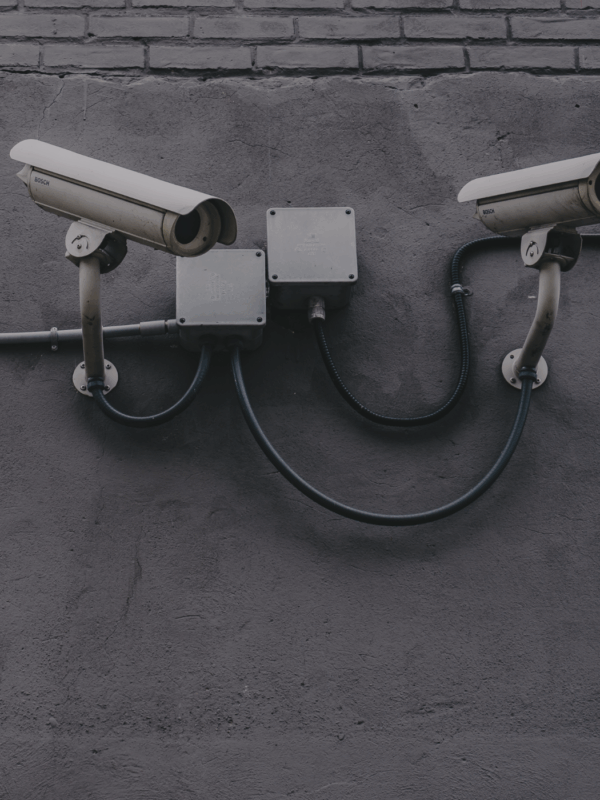 Image of white security cameras against a grey wall.