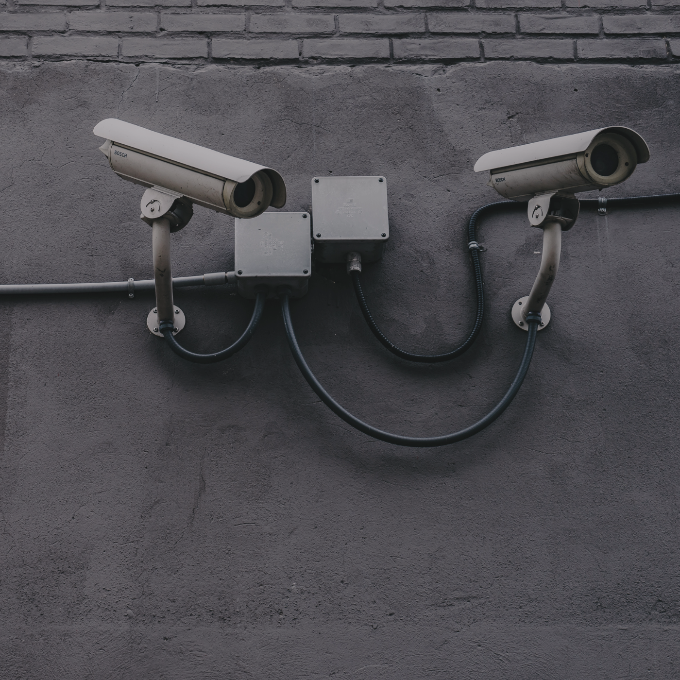 Image of white security cameras against a grey wall.