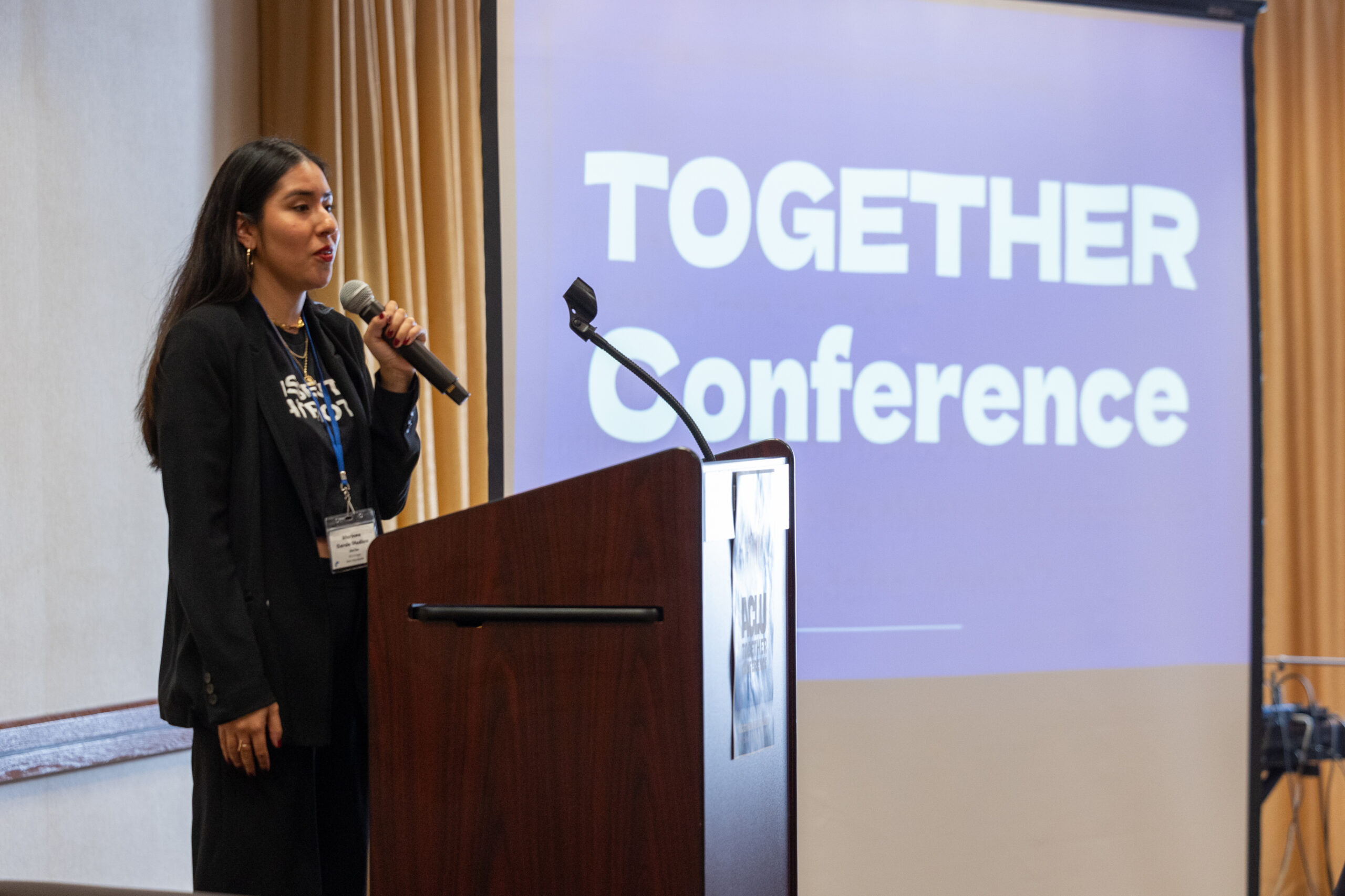 Mariana holds a microphone and speaks