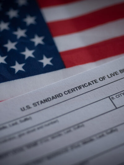 A birth certificate in front of an American flag.
