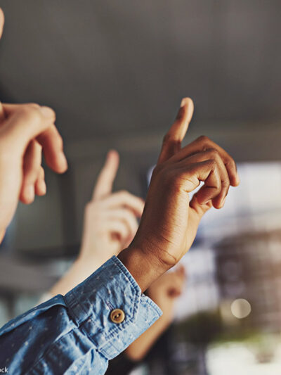 Several hands raising, one of which belongs to a Black person.