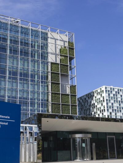 An exterior view of the International Criminal Court In The Hague, Netherlands, with the sign of with of the official logo and inscription of the International Criminal Court in the foreground.