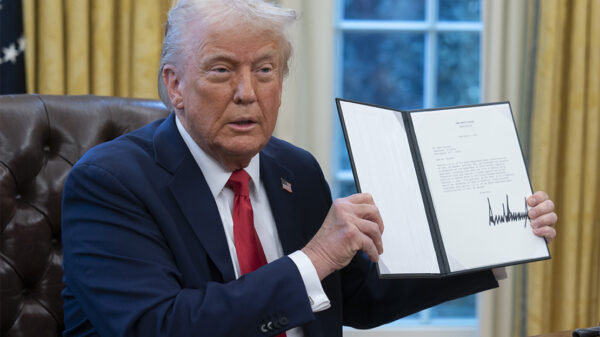 President Donald Trump holds up a recently signed executive order in the Oval Office of the White House.