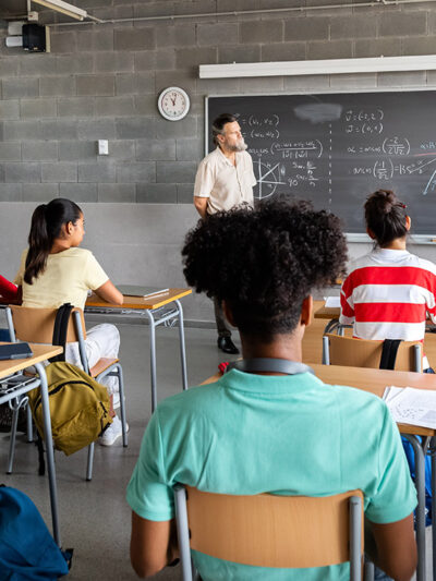 A student presenting in front of a diverse classroom.