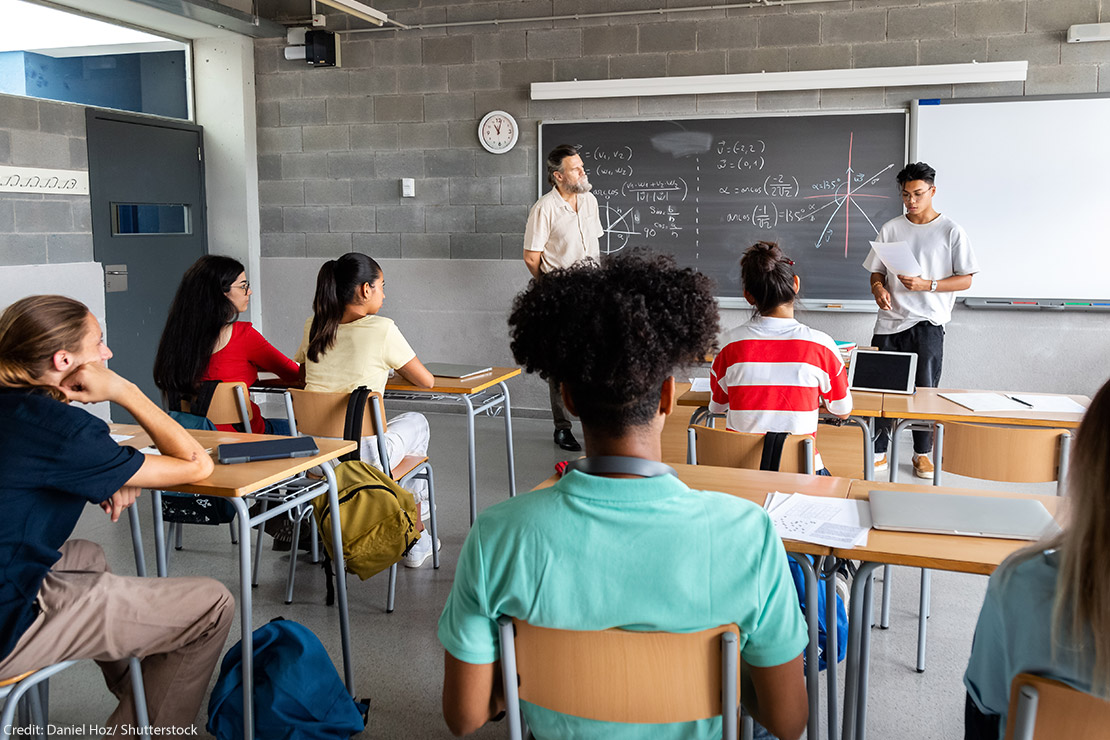 A student presenting in front of a diverse classroom.