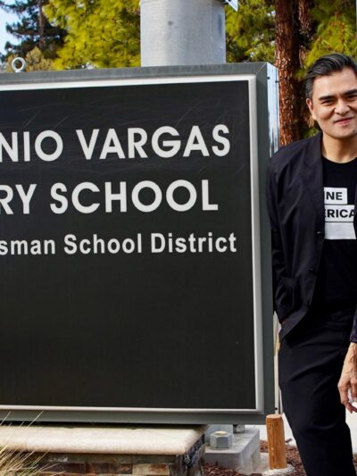 A smiling Jose Antonio Vargas and two equally joyful female family members stand to the right of a large sign that reads "JOSE ANTONIO VARGAS