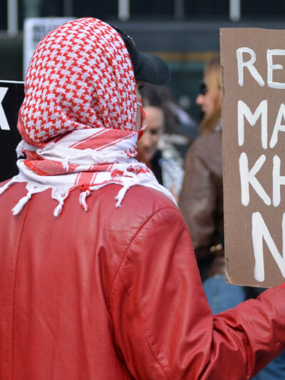 A student activist holding a sign that says "Release Mahmoud Khalil Now."