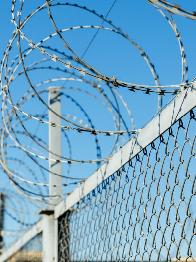 A chain link fence with razor wire running along the top.