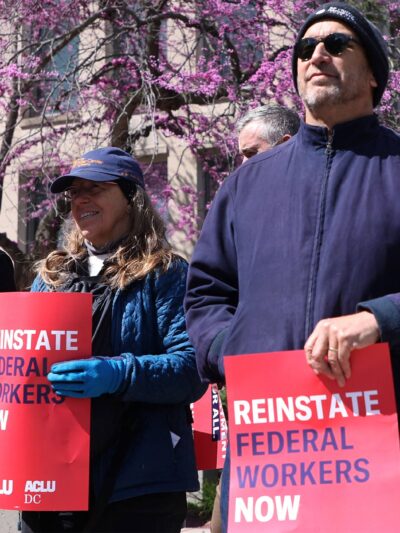Demonstrators hold signs from ACLU & ACLU DC that read" REINSTATE FEDERAL WORKERS NOW" and "EQUAL AND JUST TREATMENT FOR ALL" as they protest in support of Federal Workers at the Office of Personnel Management in Washington, DC.