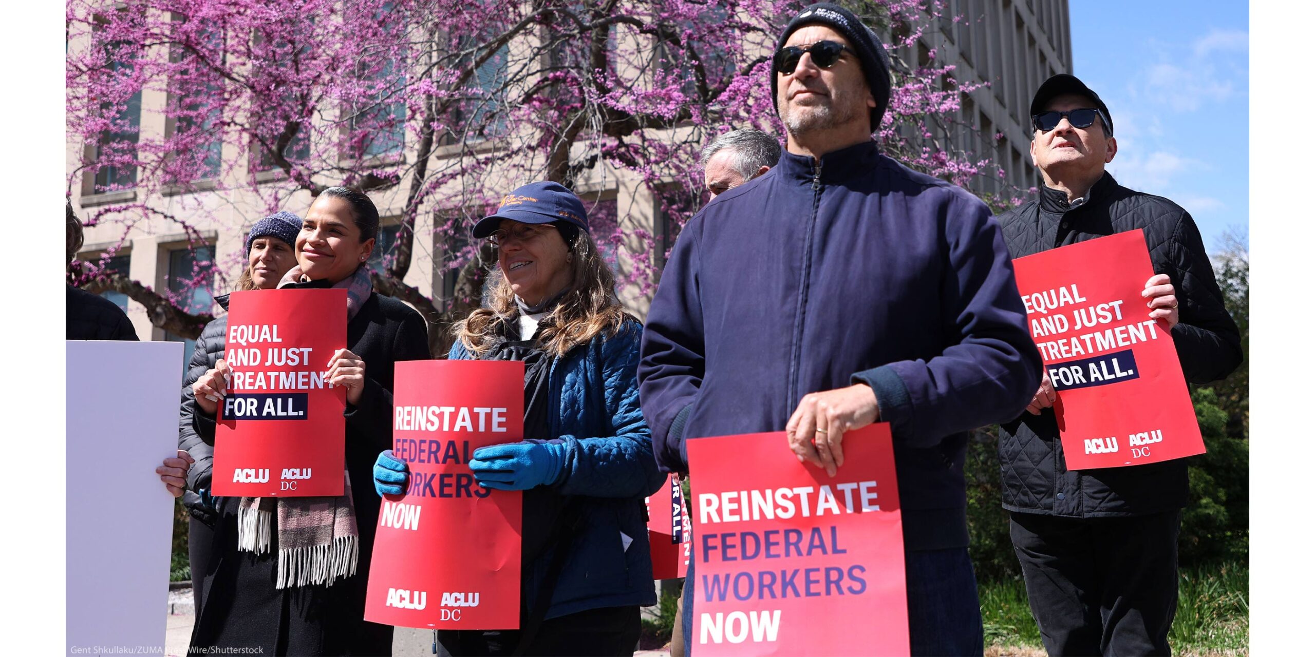 Demonstrators hold signs from ACLU & ACLU DC that read" REINSTATE FEDERAL WORKERS NOW" and "EQUAL AND JUST TREATMENT FOR ALL" as they protest in support of Federal Workers at the Office of Personnel Management in Washington, DC.