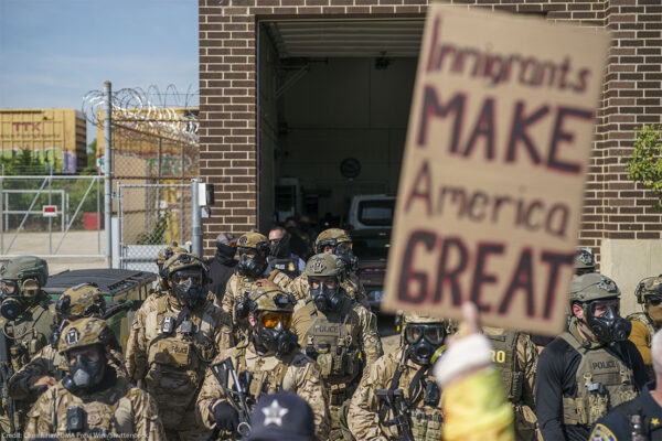 Heavily armed ICE and Border Patrol agents guard the Broadview ICE facility from peaceful protesters opposed to 'Operation Midway Blitz' in Chicagoland; their sign reads 'Immigrants Make America Great'