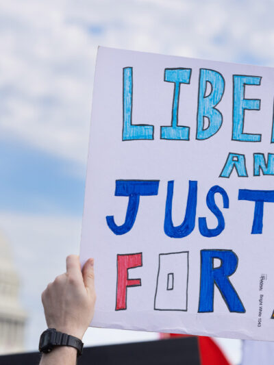 A demonstrator holds up a sign that reads, "LIBERTY AND JUSTICE FOR ALL" at the No Kings National Day of Action protest near the U.S. Capitol building in Washington, D.C., October 18, 2025.