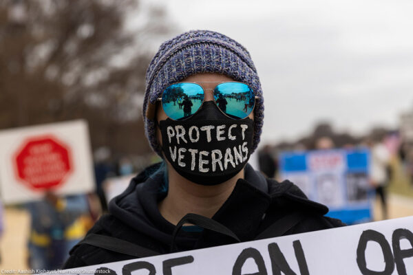 A demonstrator wears a mask with the text ''Protect Veterans'' during the ''Veterans March'' at the National Mall in Washington.