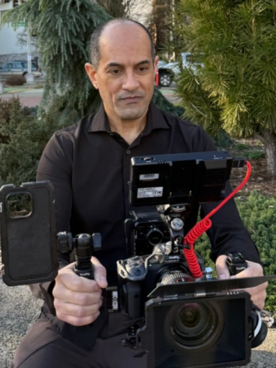 A picture of Hugo Rio holding and looking into a camera.