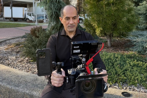 A picture of Hugo Rio holding and looking into a camera.