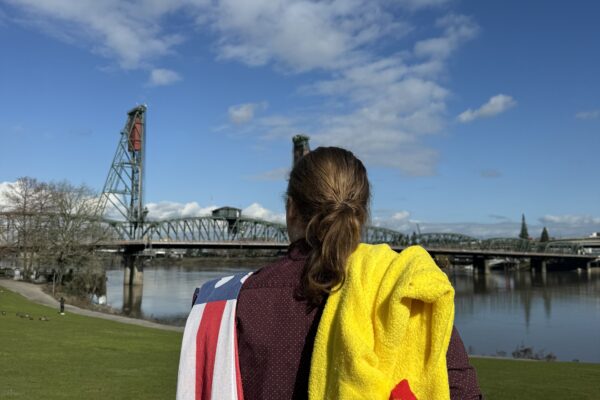 JacK Dickinson stands on the Waterfront, with his chicken suit and flag thrown over his shoulders.