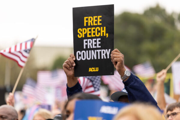 A protestor holds a sign that says Free Speech, Free Country