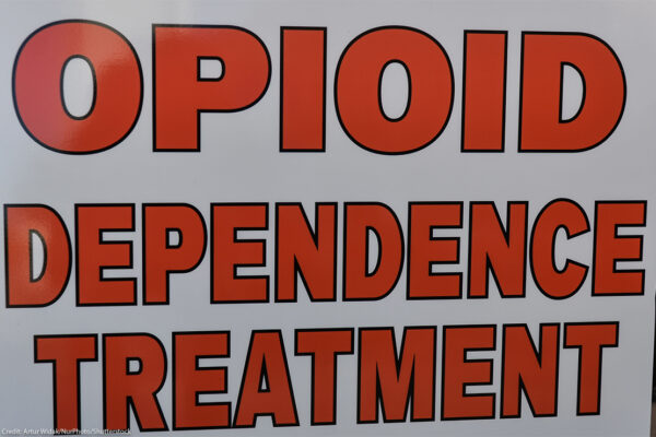 Close-up of a sign reading “OPIOID DEPENDENCE TREATMENT” in large red letters on a white background.