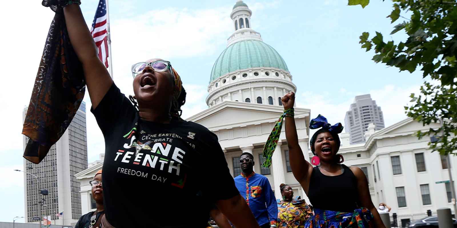 Marchers commemorating Juneteenth walking with fists raised in front of the Old Courthouse in St. Louis.