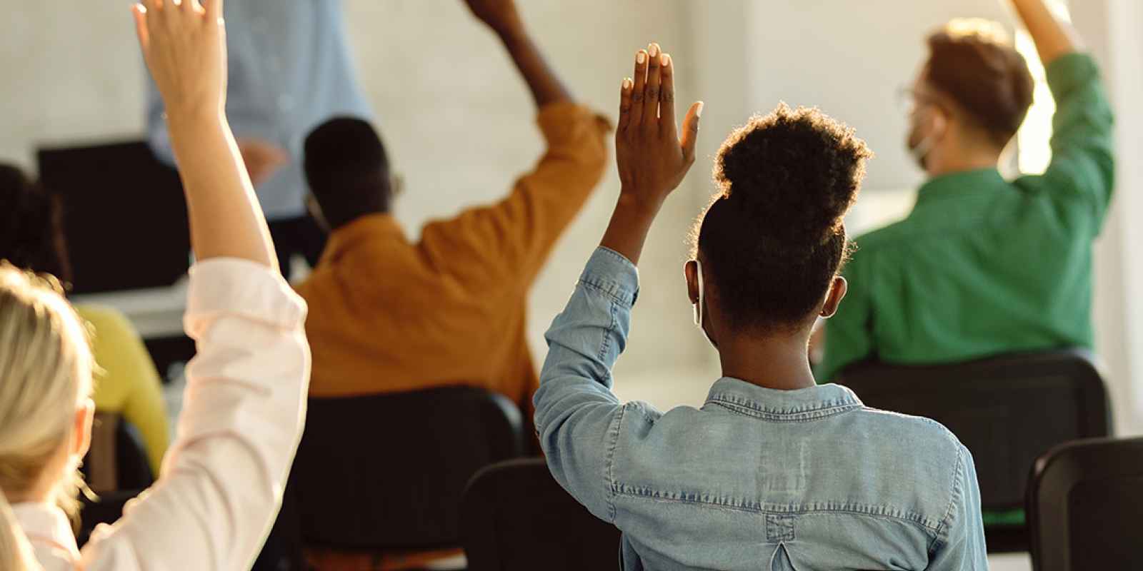 Students raising their hands in a classroom.