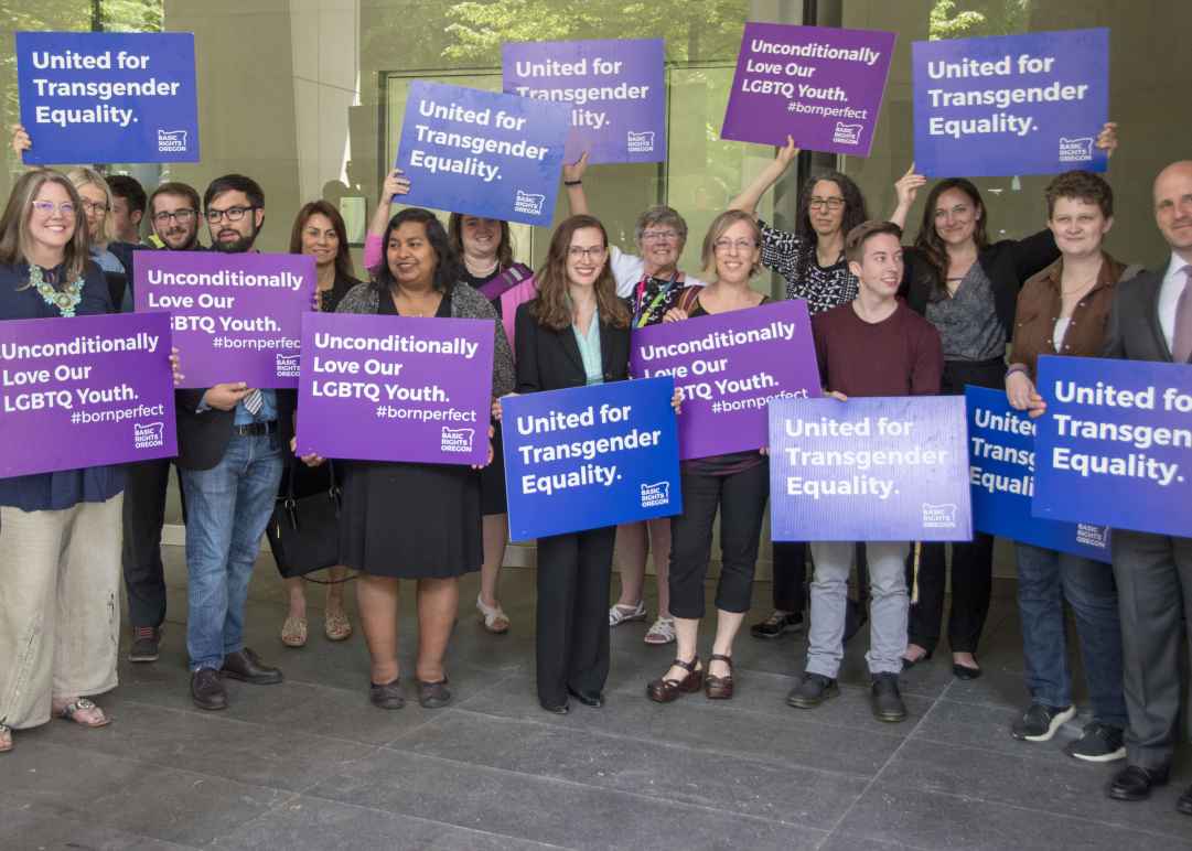 advocates outside court holding signs for transgender equality