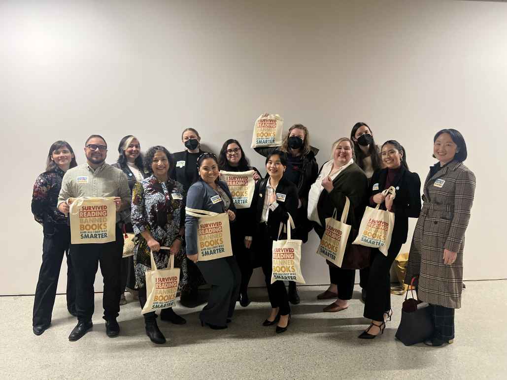 Members of the ACLU, Basic Rights Oregon, Oregon Education Association and the Oregon Library Association grouped together holding tote bags that say "I survived reading banned books and all I got was smarter."