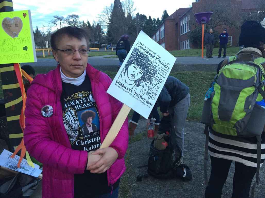 Irene Kalonji holds a sign with her son's face on it at a memorial event