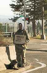 person with sign on side of road