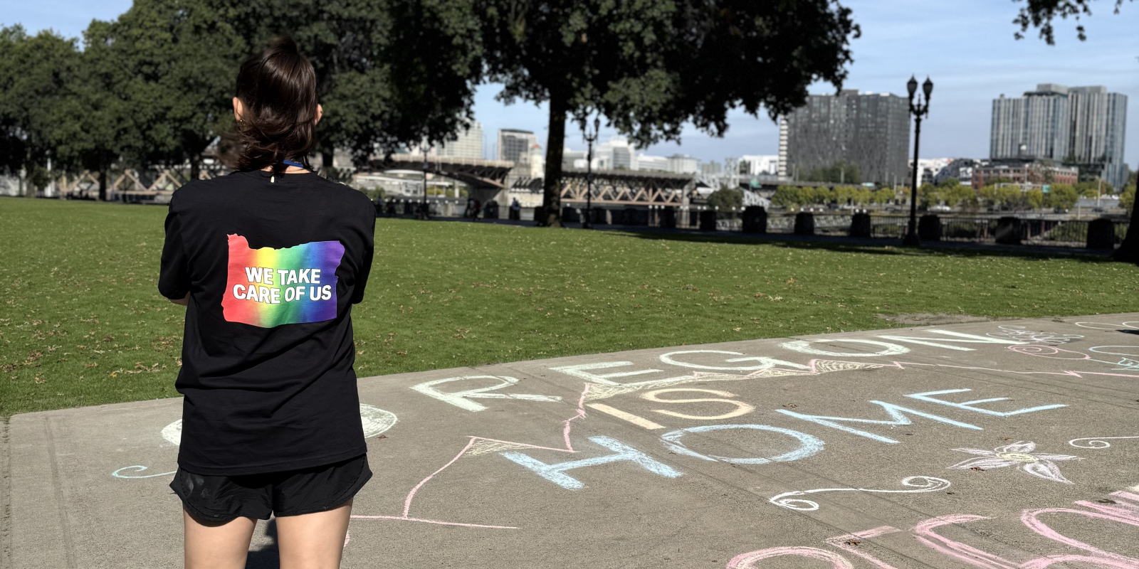ACLU member standing in front of chalk art that reads Oregon is Home