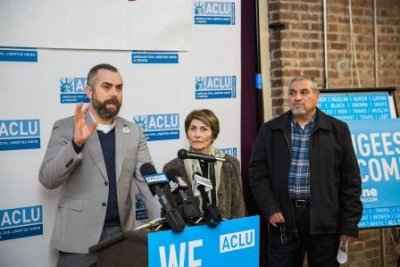 Three people stand in front of microphones at a press conference at Unite Oregon