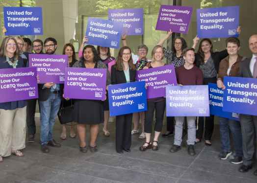 advocates outside court holding signs for transgender equality