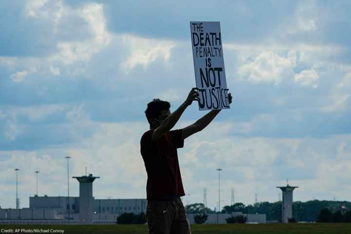 A man holding a sign that says "Death Penalty is Not Justice."