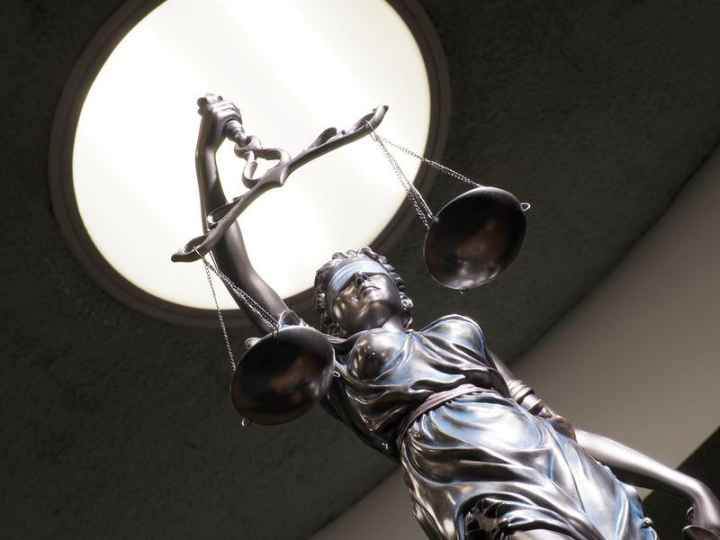 Image of brass statue holding scales in courtroom