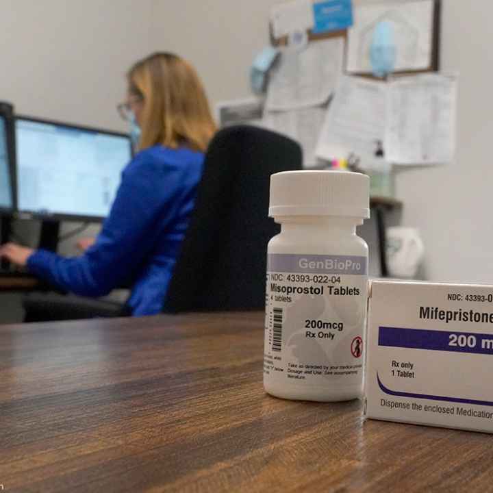 A box of the drug mifepristone pictured in front of a women on a computer.
