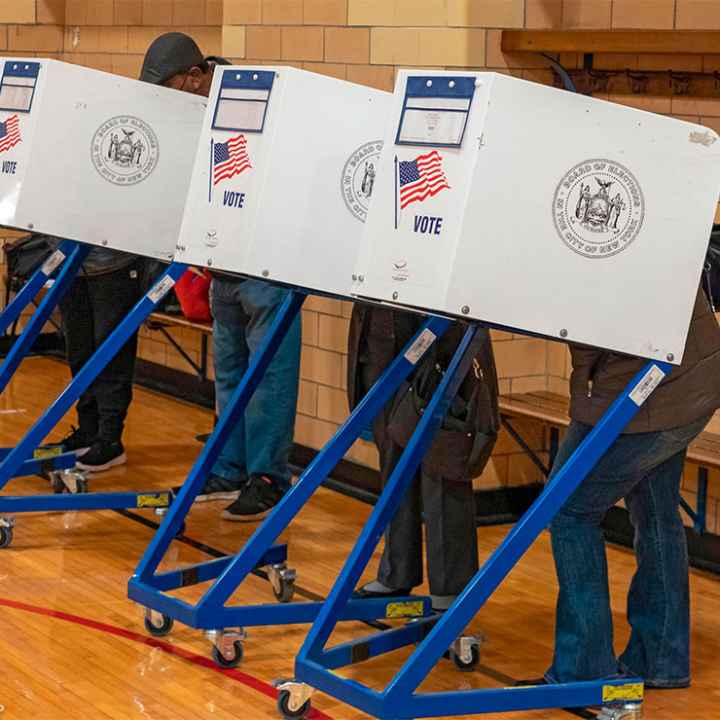 Four people, with their faces and bodies hidden behind voting privacy shields, are casting their votes for the midterm elections on Election Day November 08, 2081 in a New York City public school.