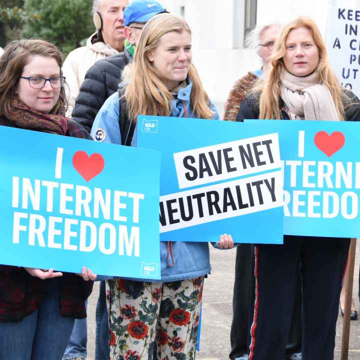 people holding signs that say i (heart) internet freedom and Save Net Neutrality on the capitol steps in Salem