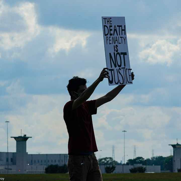 A man holding a sign that says "Death Penalty is Not Justice."