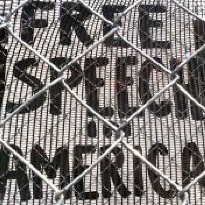 Free speech in America A sign reading 'Free Speech in America' is visible through a chainlink fence
