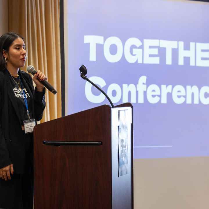 Mariana holds a microphone and speaks