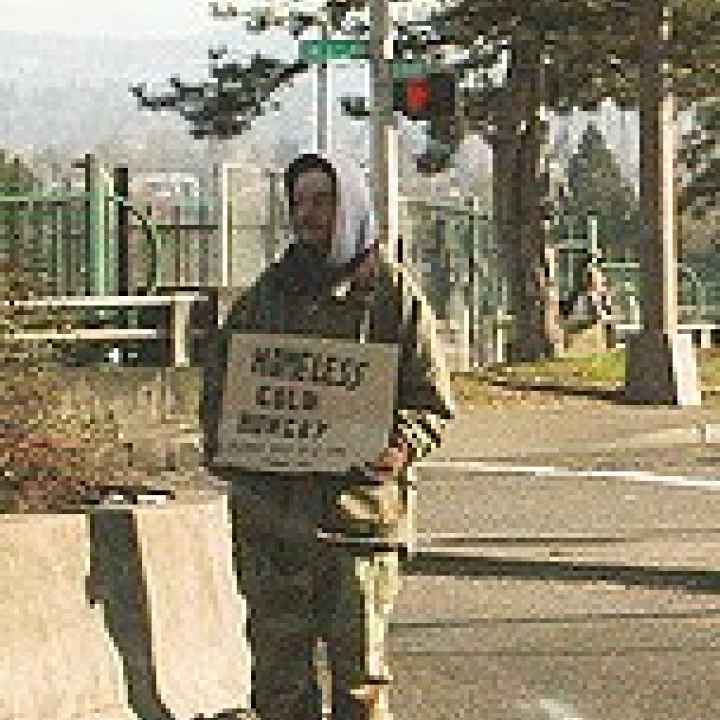 person with sign on side of road