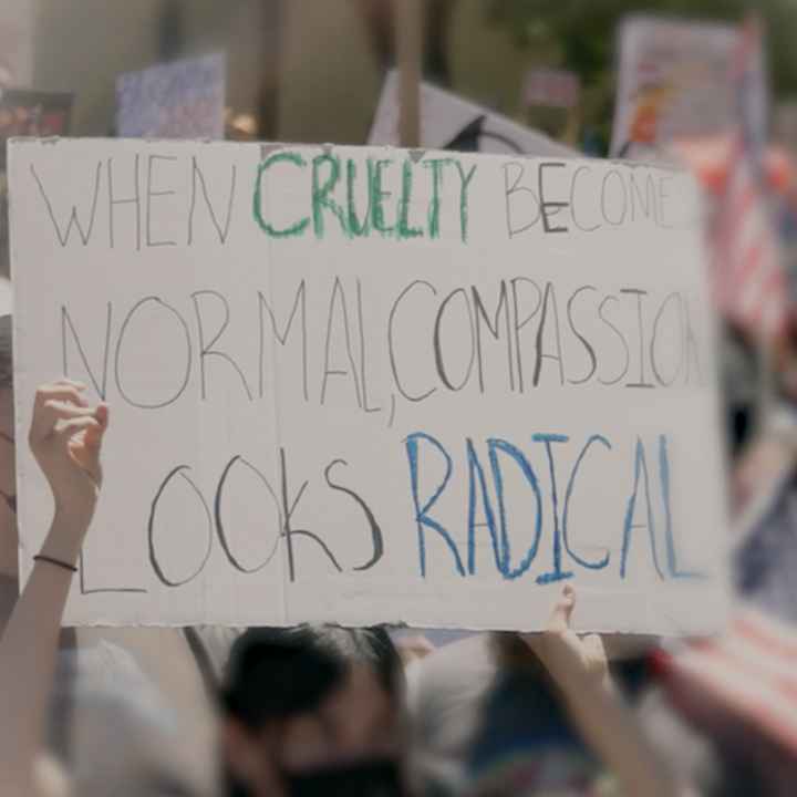 A demonstration sign that say "When Cruelty Becomes Normal, Compassion Looks Radical."