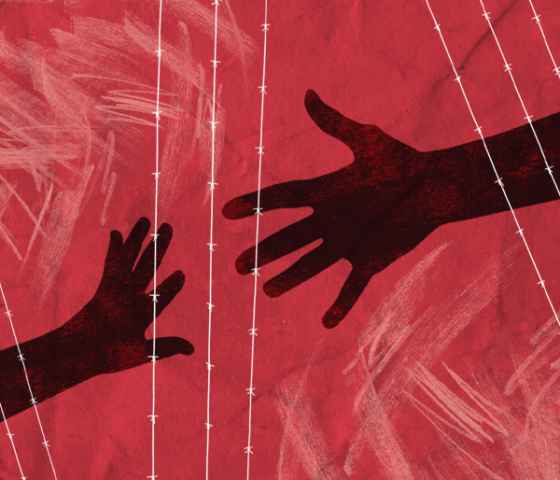 Two hands reaching to each other through barbed wire