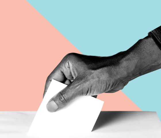 Hand placing ballot in box.
