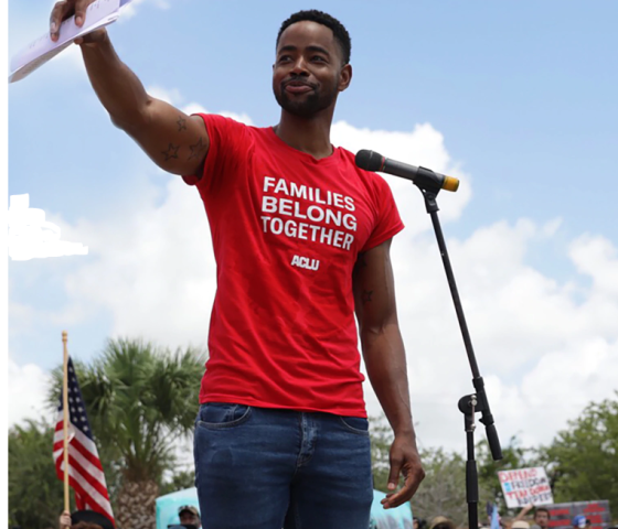 rally speaker with t-shirt that reads "families belong together"