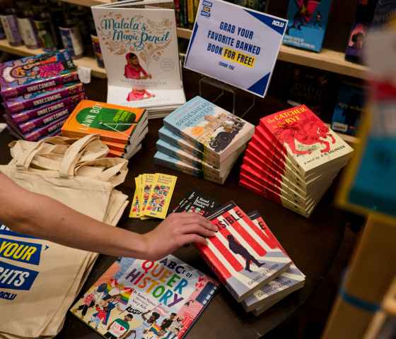 A hand reaches for a book among banned books.